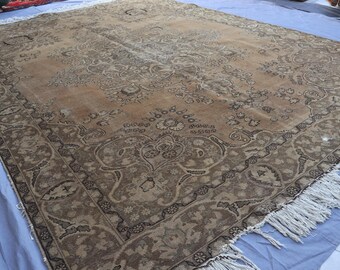 May include: A large, rectangular rug with an intricate floral pattern in shades of brown and beige. The rug has a detailed border and fringed edges, showcasing a vintage aesthetic. The design features a central medallion and corner motifs.