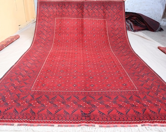 May include: A red rug with a geometric pattern. The rug has a dark red background with a lighter red pattern. The rug is fringed on all sides.
