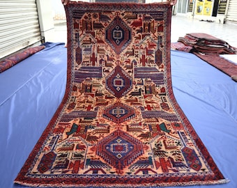 May include: A rectangular hand-knotted rug featuring a cream-colored background with a repeating pattern of dark blue and red diamond-shaped medallions. The design includes various stylized animal and bird motifs in red, blue, and green tones.