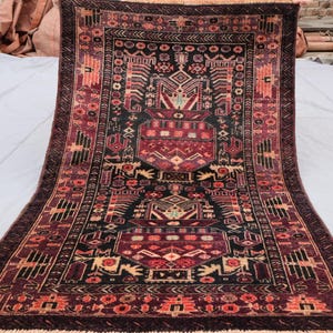 Può includere: Un tappeto persiano tradizionale con uno schema di colori rosso scuro, nero e crema. Il tappeto presenta un medaglione centrale con intricati motivi geometrici e motivi floreali. Il tappeto ha un bordo con frange.