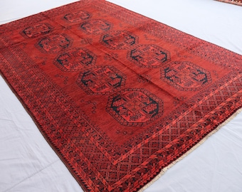 May include: A red rug with a black geometric pattern. The rug has a fringe border.