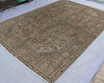 May include: A large, rectangular, vintage rug with an intricate, all-over pattern in shades of brown, beige, and muted red. The rug features a detailed border with floral and geometric motifs, and measures approximately 9 x 12 feet.