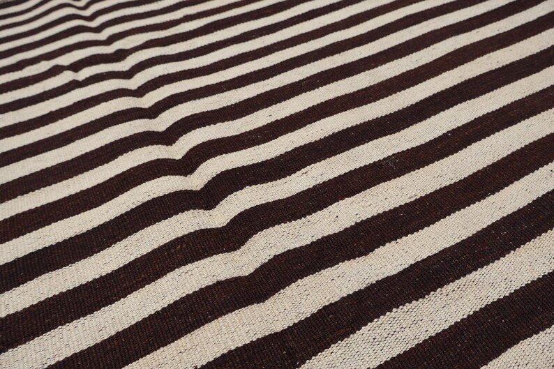 May include: A close-up of a brown and white striped fabric. The fabric has a woven texture and is made of natural fibers.