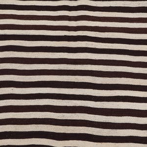 May include: A close-up of a striped fabric with alternating brown and white stripes. The fabric is woven and has a slightly textured surface.