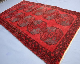 May include: A red rug with a black and gray geometric pattern. The rug has a fringe border.