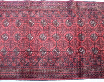 Puede incluir: Una alfombra roja y negra con un diseño geométrico. La alfombra tiene un borde con flecos.
