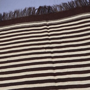 May include: A brown and white striped rug with fringe on all sides.