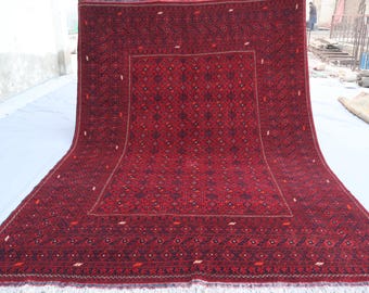 May include: A red and black patterned rug with a geometric design. The rug has a fringe border and is made of wool.