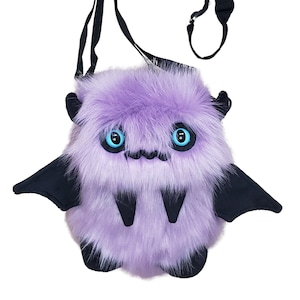 Może przedstawiać: Fioletowa pluszowa torba na ramię w kształcie kreskówkowego nietoperza, z czarnymi skrzydłami i regulowanym czarnym paskiem. Torba ma duże niebieskie oczy i dwa kły.