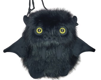 May include: Black plush bat-shaped crossbody bag with yellow eyes and a furry texture.