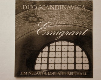 Könnte beinhalten: Sepiafarbenes Albumcover für „Emigrant“ von Duo Scandinavica. Das Bild zeigt ein großes Bogenfenster mit einem Rastermuster, einen dekorativen Kronleuchter und die Namen Jim Nelson & Lori-Ann Reinhall. Der Titel „Emigrant“ ist in eleganter Schrift gehalten.
