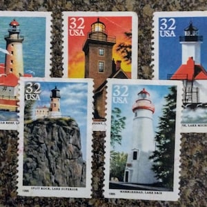 Könnte beinhalten: Fünf US-amerikanische Briefmarken mit Leuchttürmen. Jede Briefmarke hat einen Wert von 32 Cent. Die Briefmarken zeigen verschiedene Leuchtturmdesigns vor blauem Himmel und Wasser. Die Briefmarken stammen aus den Jahren 1990 und 1995.