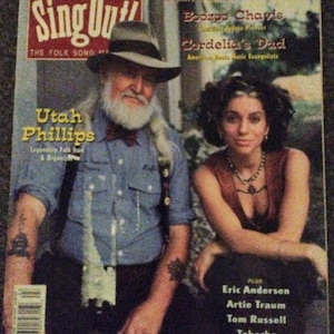 Könnte beinhalten: Ein Vintage-Magazin-Cover mit dem Titel "Sing Out!" mit Utah Phillips und einer Frau. Das Magazin trägt den Untertitel "The Folk Song Magazine". Das Cover enthält Text über Aufnahmen und Artikel. Der Hintergrund hat ein verblasstes, gealtertes Aussehen.