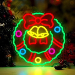 Peut inclure: Une couronne de Noël au néon avec un nœud rouge, des cloches jaunes et des accents colorés. La couronne est soulignée de vert et comporte des lumières circulaires rouges, roses et bleues. Décorations de vacances festives.