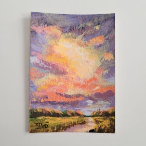 May include: A rectangular painting depicting a sunset landscape with vibrant orange, yellow, and purple clouds above a dark green field and a path. The artwork features visible brushstrokes and the signature STAHL in the bottom left corner.
