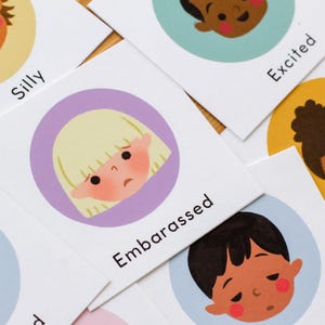 May include: Cards with illustrations of children's faces expressing different emotions. The cards have text labels such as "Embarrassed" and "Excited". The illustrations are in a circular design with a white background.
