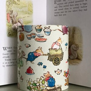 Op de afbeelding: Cilindrische lampenkap met een grillige illustratie van bosdieren, waaronder muizen en eekhoorns, die verschillende activiteiten uitvoeren. Het ontwerp bevat elementen zoals cupcakes, taarten en bloemmotieven, waardoor een sprookjesachtige uitstraling ontstaat.