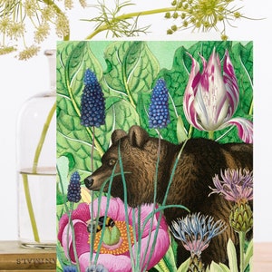 May include: A brown bear peeking out from behind a pink flower and green leaves. The bear is surrounded by other flowers, including bluebells, purple and white tulips, and blue forget-me-nots.