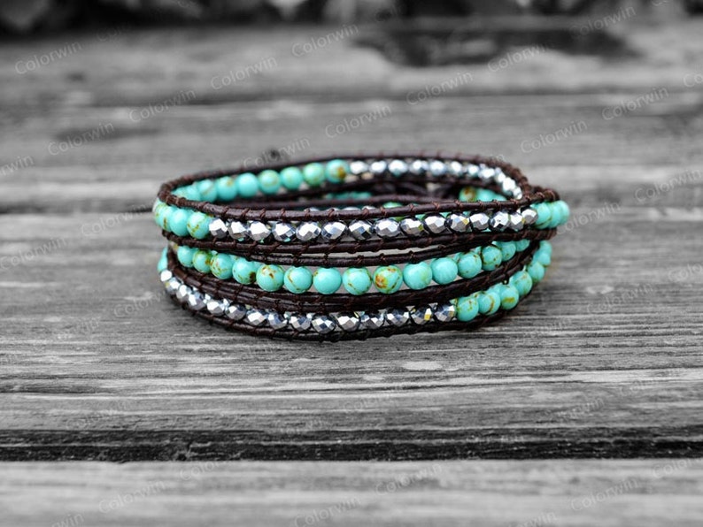 May include: A turquoise and silver wrap bracelet with brown leather cord. The bracelet is made with small round turquoise beads and silver beads.