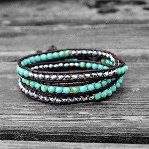 May include: A turquoise and silver beaded wrap bracelet with brown leather cord. The bracelet is wrapped around itself three times.