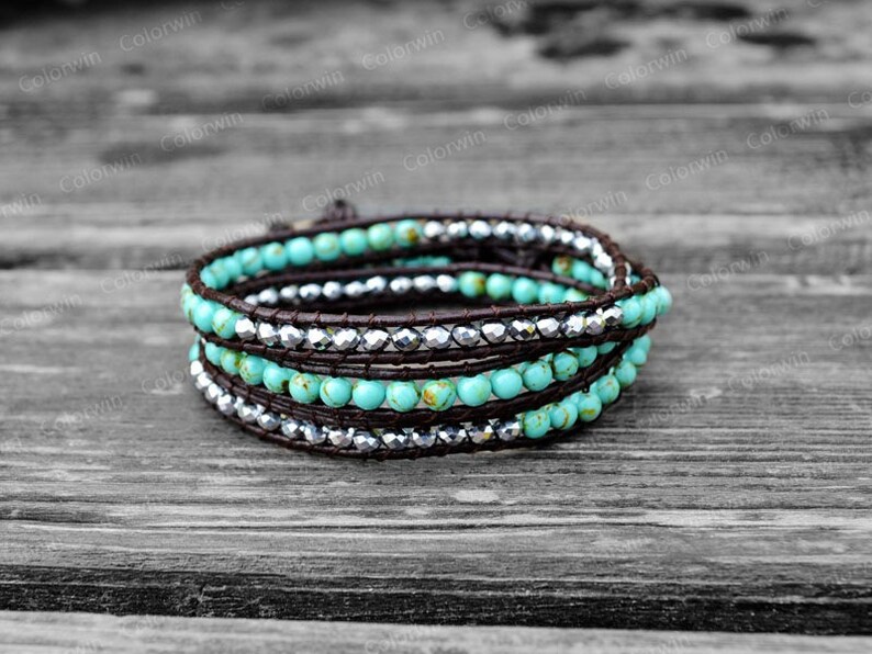 May include: A turquoise and silver beaded wrap bracelet with brown leather cord. The bracelet is wrapped around itself three times.