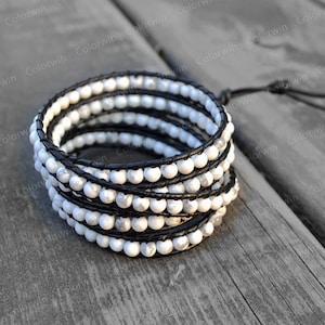 May include: A multi-strand bracelet with white howlite beads and black leather wrappings. The bracelet is tied with a black leather cord.