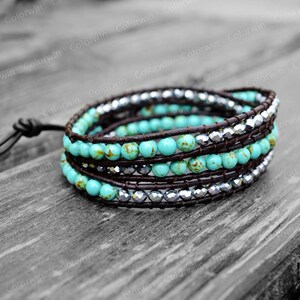 May include: A turquoise and silver wrap bracelet with brown leather cord. The bracelet is made of small turquoise beads and silver beads, and it is wrapped around a brown leather cord.