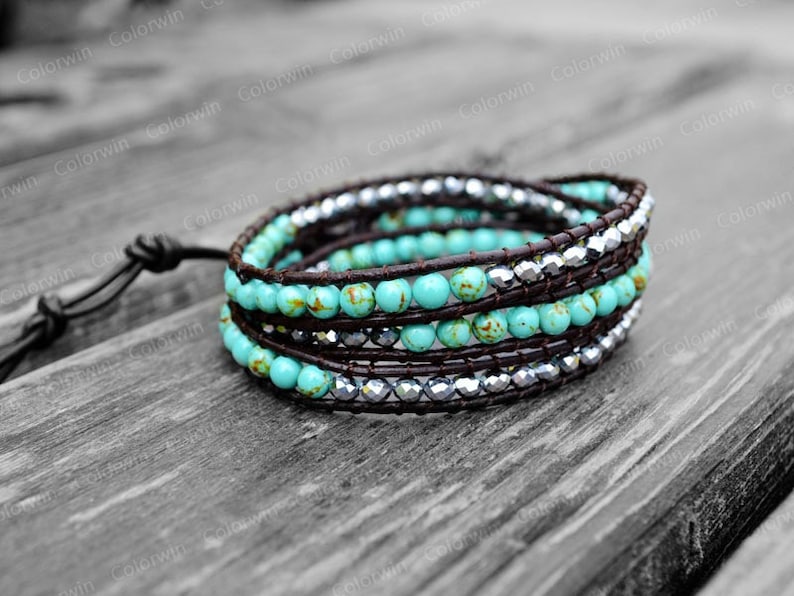 May include: A turquoise and silver wrap bracelet with brown leather cord. The bracelet is made of small turquoise beads and silver beads, and it is wrapped around a brown leather cord.