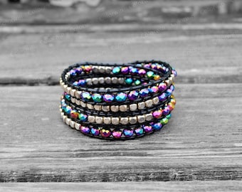 Puede incluir: Pulsera envolvente con múltiples hebras de cuero negro y cuentas iridiscentes multicolores. La pulsera también incluye cuentas cuadradas de color dorado. Diseñada para envolverse alrededor de la muñeca varias veces.