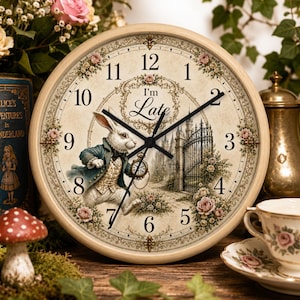 May include: A round wall clock with a cream-colored face featuring black numerals, a central illustration of a rabbit in a blue coat holding a pocket watch, a wrought iron gate, and floral accents. The text "I'm Late" is printed in the center.