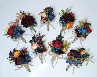 May include: Ten small bouquets of artificial flowers in shades of burgundy, red, blue, and yellow. Each bouquet is tied with twine and features a variety of flower types, including roses, berries, and greenery.