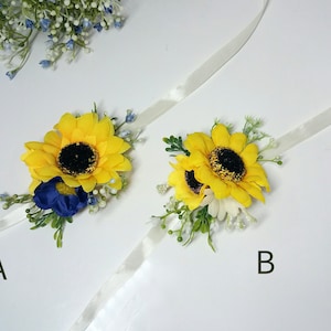 May include: Two sunflower wrist corsages with white ribbon. Corsage A features a blue flower and corsage B features a white flower.