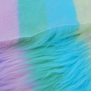 May include: A close-up of a soft, fluffy fabric with a gradient of colours, starting with a light purple and transitioning to a vibrant turquoise.
