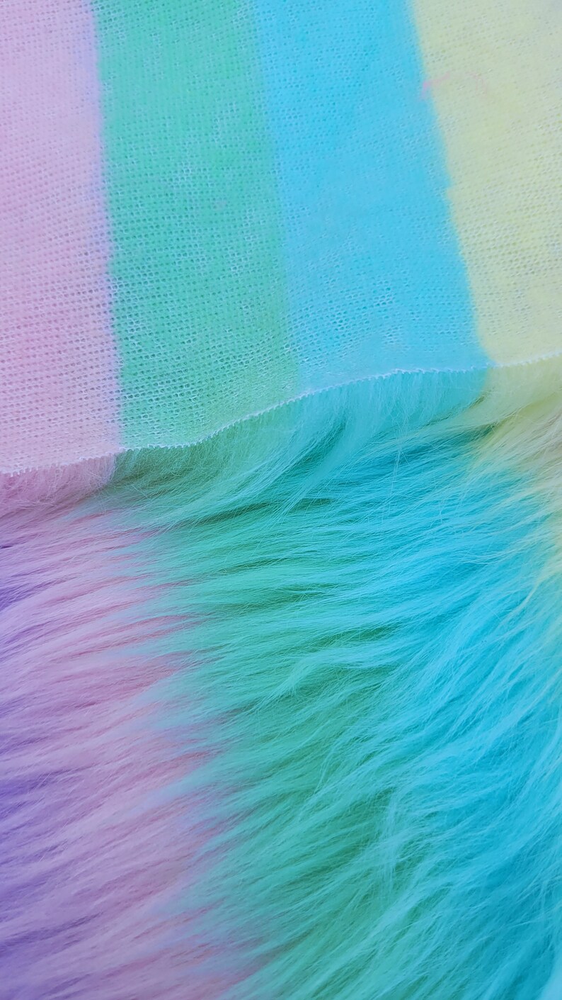 May include: A close-up of a soft, fluffy fabric with a gradient of colours, starting with a light purple and transitioning to a vibrant turquoise.