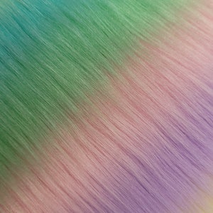 May include: A close-up of a rainbow ombre hair extension. The hair is straight and the colours transition from yellow to green to purple.