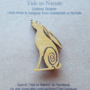 May include: A wooden cutout of a hare, painted in a light yellow colour. The hare is sitting up with its ears perked and its tail raised. The hare is a popular symbol of good luck and is often used in decorative art.