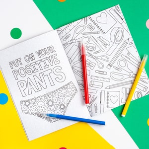 Puede incluir: Un libro para colorear con una ilustraci&oacute;n en blanco y negro de ropa interior con un patr&oacute;n de corazones y estrellas. El texto en la portada dice "Put on your positive pants". La parte posterior del libro tiene una ilustraci&oacute;n en blanco y negro de varios &uacute;tiles escolares.