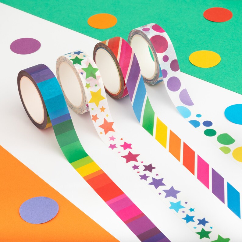 Puede incluir: Vista a&eacute;rea de cinco rollos de cinta adhesiva decorativa con dise&ntilde;os coloridos. Los dise&ntilde;os de la cinta incluyen rayas, estrellas y lunares en un arco&iacute;ris de colores. El fondo presenta c&iacute;rculos coloridos dispersos sobre superficies blancas y verdes.