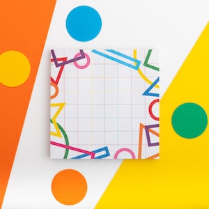 May include: A white notepad with a grid pattern and colorful geometric shapes. The notepad is surrounded by colorful circles on a white and yellow background.