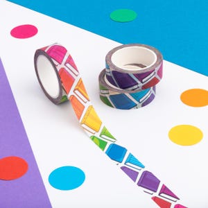 Peut inclure: Rouleaux de ruban adh&eacute;sif washi d&eacute;coratifs avec un motif de livres color&eacute;s. Un rouleau est d&eacute;roul&eacute;, montrant le motif des livres aux couleurs de l'arc-en-ciel. Deux autres rouleaux sont empil&eacute;s. Fond blanc avec confettis color&eacute;s.