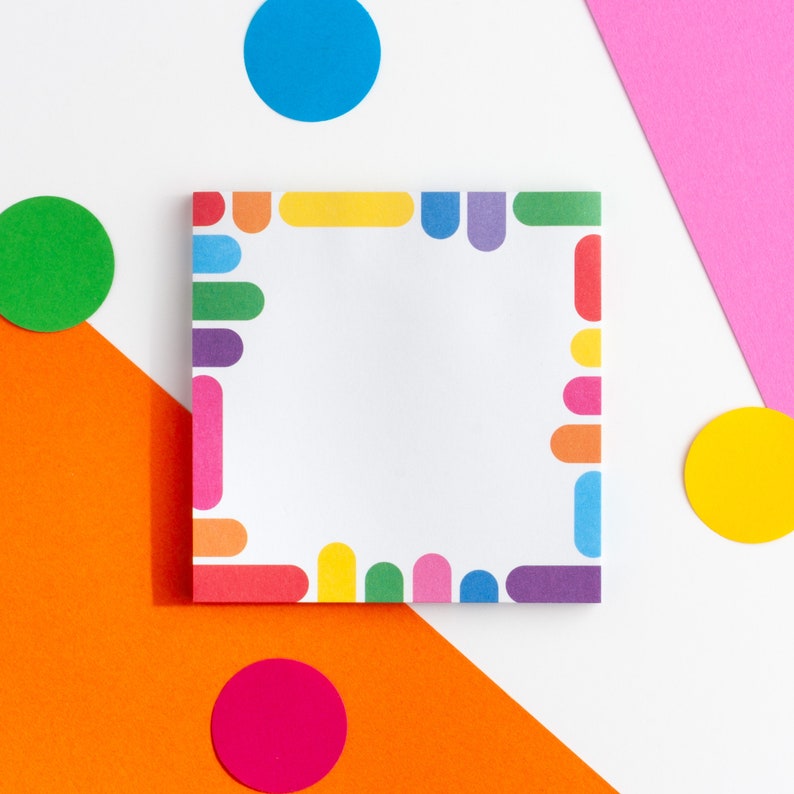 May include: A white notepad with a colorful border of circles and semi-circles. The notepad is on a white surface with orange, pink, and green circles.
