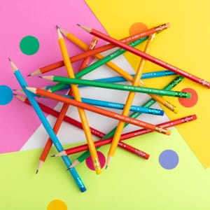 Pu&ograve; includere: Una collezione di matite colorate con frasi motivazionali come "Believe You Can & You Will" e "Always Choose Kindness" stampate sopra. Le matite, in rosso, blu, verde e giallo, sono disposte su uno sfondo vivace.