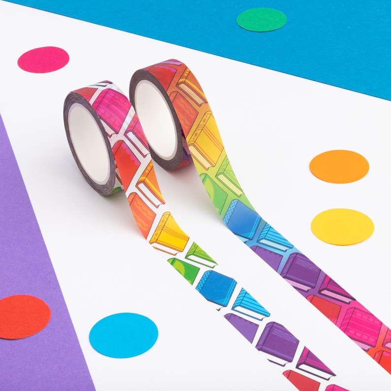 Peut inclure: Deux rouleaux de ruban adh&eacute;sif d&eacute;coratif avec un motif de livres arc-en-ciel. Le ruban est dans les tons de rouge, orange, jaune, vert, bleu et violet. Le fond est blanc avec des confettis circulaires color&eacute;s.