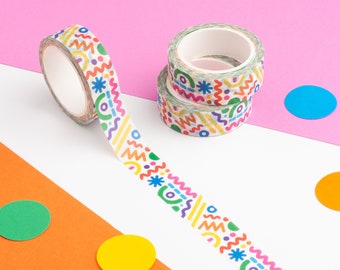 May include: A roll of colorful washi tape with a geometric pattern. The tape is unrolled and shows the design, which includes circles, lines, and stars. The tape is on a pink, white, and orange background with colorful circles.