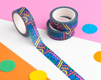May include: A roll of colorful patterned washi tape with a blue background and geometric shapes in pink, yellow, orange, and green. The tape is unrolled and there are two rolls of the same tape stacked on top of each other.