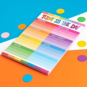 Puede incluir: Un bloc de notas colorido con el texto "Today is the day" en letras de arco&iacute;ris. El bloc de notas est&aacute; dividido en secciones para la ma&ntilde;ana, la tarde, la noche, la recompensa, las notas y un objetivo principal. Tambi&eacute;n hay una secci&oacute;n para "No olvides".