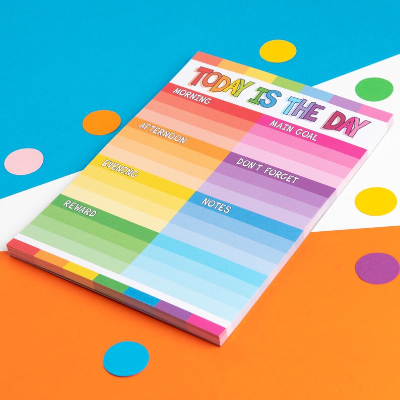 Puede incluir: Un bloc de notas colorido con el texto "Today is the day" en letras de arco&iacute;ris. El bloc de notas est&aacute; dividido en secciones para la ma&ntilde;ana, la tarde, la noche, la recompensa, las notas y un objetivo principal. Tambi&eacute;n hay una secci&oacute;n para "No olvides".