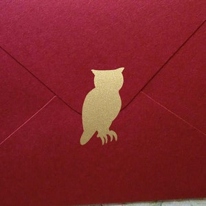 May include: Red envelope with a gold owl silhouette.