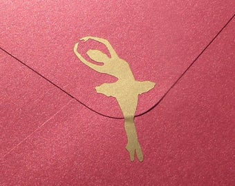 May include: A red envelope with a gold ballerina silhouette. The envelope is closed and has a textured, glittery surface. The ballerina is in a graceful pose, arms raised above her head.