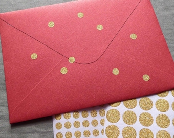 May include: A red envelope with gold glitter dot stickers. The envelope is rectangular with a flap closure and gold dots scattered across the front. A sheet of gold glitter dot stickers is next to the envelope.